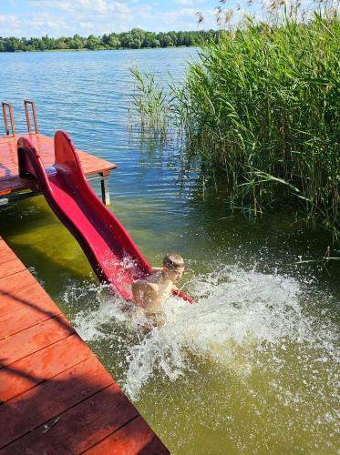 a boy in the water with a slide in the water at GłuszaSpot Dom Freja in Bytoń