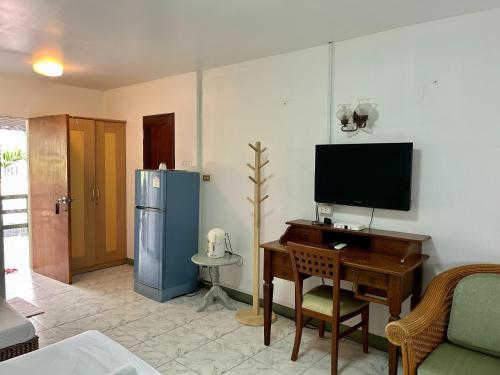 a living room with a desk with a television and a refrigerator at Baan Napapan Beach Front, Hua Hin in Hua Hin