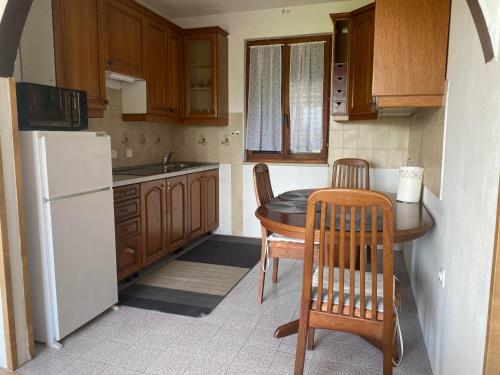 cocina con mesa, sillas y nevera blanca en Apartma Bossamarino, en Koper