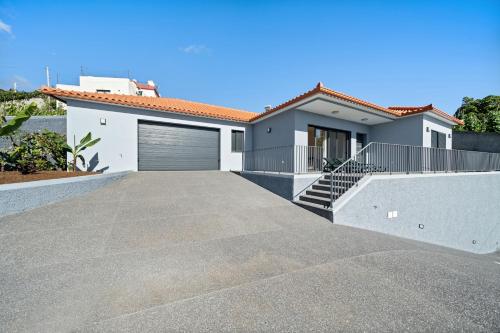 a house with a driveway and a garage at Calheta Paradise Holiday Home - Free Parking & Views in Arco da Calheta