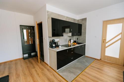 a kitchen with black cabinets and a wooden floor at Apartamenty Krzywa in Krosno