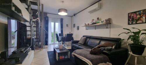 un salon avec un canapé en cuir noir et une table dans l'établissement Vincent VAN GOGH, à Mériel