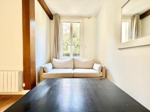 un salon avec un canapé et une fenêtre dans l'établissement Appartement - Paris 16 - Passy, à Paris