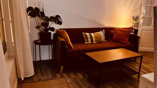 un salon avec un canapé marron et une table dans l'établissement Grand Appartement neuf a côté de stade de Paris, à La Courneuve