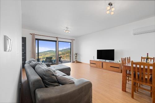 a living room with a couch and a flat screen tv at Calheta Paradise Holiday Home - Free Parking & Views in Arco da Calheta
