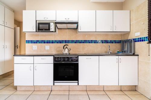 a kitchen with white cabinets and a black appliance at ATKV Natalia in Kingsburgh