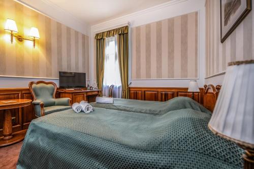 a bedroom with a bed with two towels on it at Kastélyhotel Sasvár Resort in Parádsasvár
