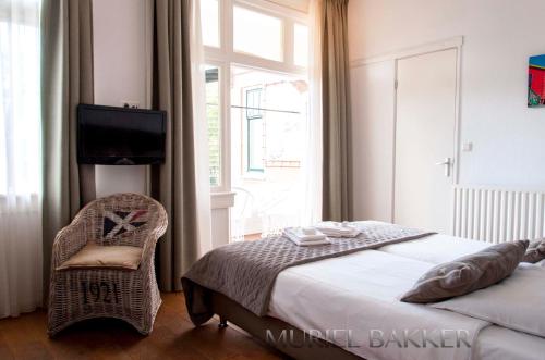 a bedroom with a bed and a chair and a television at Dijkstra Hotels in Bergen