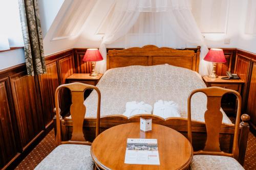 a bedroom with a bed with a table and two chairs at Kastélyhotel Sasvár Resort in Parádsasvár