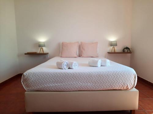 a bedroom with a large white bed with two pillows at Vicentina Rooms & Apartments - Duna Parque Group in Vila Nova de Milfontes