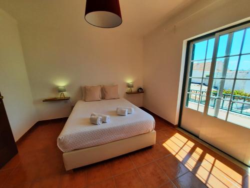 una camera da letto con un letto e una grande finestra di Vicentina Rooms & Apartments - Duna Parque Resorts & Hotels a Vila Nova de Milfontes