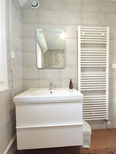 une salle de bain blanche avec un lavabo et un miroir dans l'établissement Le Balnéo Duplex avec balcon - Riva Bella Plage, à Ouistreham