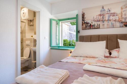 a bedroom with a bed with a window and a bathroom at Apartman Andro in Stomorska