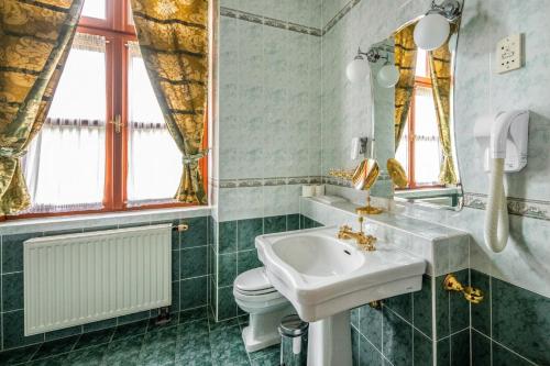 a bathroom with a sink and a toilet and a mirror at Kastélyhotel Sasvár Resort in Parádsasvár