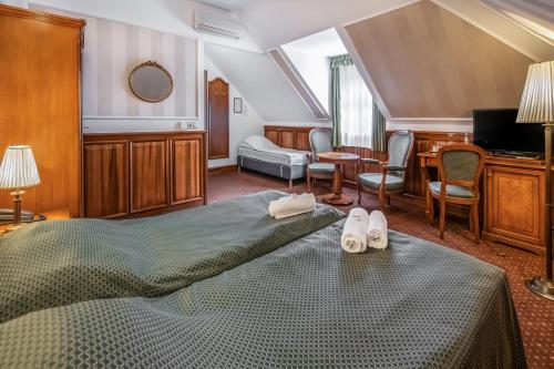 a bedroom with a bed and a desk and chairs at Kastélyhotel Sasvár Resort in Parádsasvár