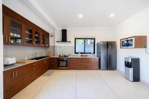 a kitchen with wooden cabinets and stainless steel appliances at Golden Sands Villa only 15 minutes walk to beach in Ban Lum Fuang