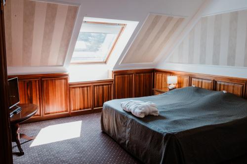 a bedroom with a bed with a towel on it at Kastélyhotel Sasvár Resort in Parádsasvár