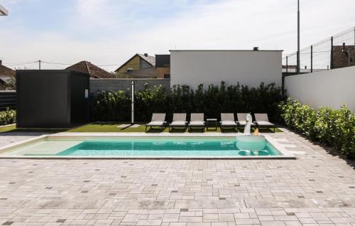 a swimming pool in a backyard with chairs and a swimming pool at Beautiful Home In Rokovci With Sauna in Rokovci