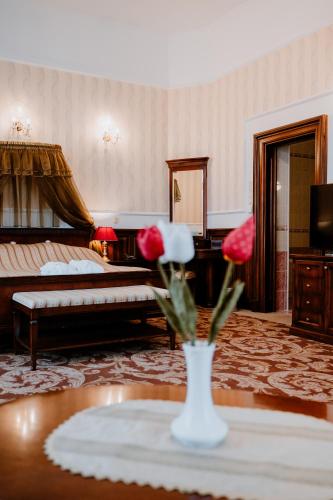 a living room with a bed and a vase of flowers on a table at Kastélyhotel Sasvár Resort in Parádsasvár