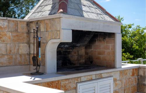 a brick fireplace with a roof on a house at Nice Home In Sumartin With Wifi in Sumartin