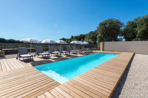 une piscine avec des chaises et une terrasse en bois dans l'établissement Le Mas des Aracil 2 - Appt climatisé avec piscine, à Suze-la-Rousse