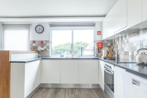 a kitchen with white cabinets and a clock on the wall at Viriato's House in Ribeira Grande