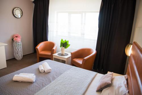 a bedroom with a bed and two chairs and a window at MBI Travel Inn in Craiova