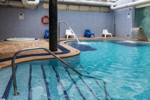 a large swimming pool with blue chairs in a building at Hotel Milagros Golf in Mogro
