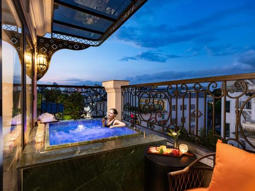 a woman sitting in a hot tub on a balcony at GRAND HOTEL du LAC Hanoi in Hanoi