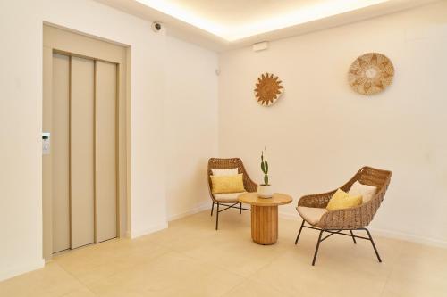 a hallway with two chairs and a table and a clock at Excelsior Estudios & Apartamentos in San Antonio