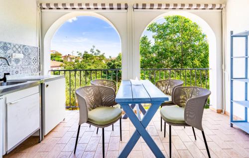 a kitchen with a blue table and chairs on a balcony at Amazing Apartment In Fazana With Wifi in Fažana