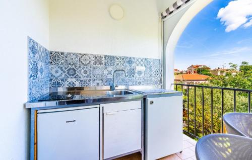 a kitchen with a sink and a balcony at Amazing Apartment In Fazana With Wifi in Fažana