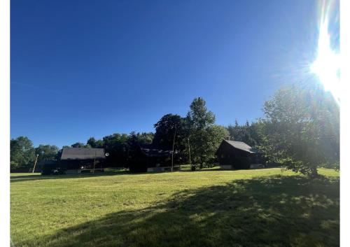 a grassy field with houses and the sun in the sky at Areál Kamínka - SRUB in Roštín