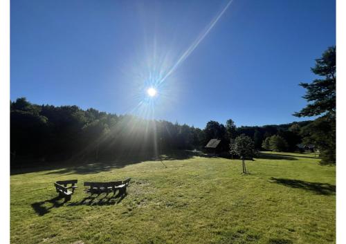 a bench in a field with the sun in the sky at Areál Kamínka - SRUB in Roštín