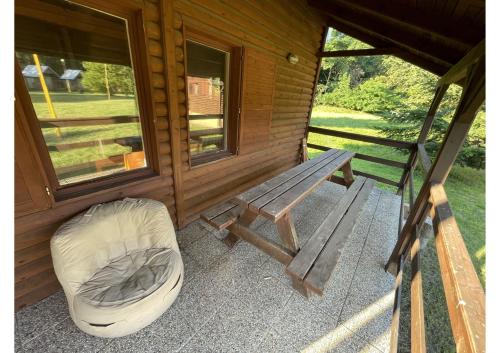 a bench and a ottoman on the porch of a cabin at Areál Kamínka - SRUB in Roštín
