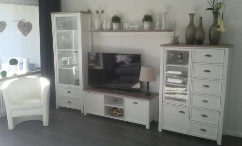 a living room with a tv and a white cabinet at Ferienwohnung Steffens Hahnenklee in Hahnenklee-Bockswiese