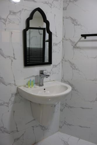 a white bathroom with a sink and a mirror at New Rafi Hotel in Amman