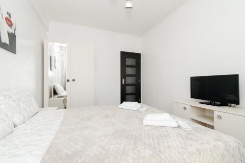 a white bedroom with a large bed and a tv at ERA RENT Apartments in Chişinău