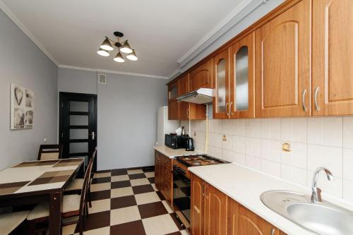 a kitchen with wooden cabinets and a checkerboard floor at ERA RENT Apartments in Chişinău