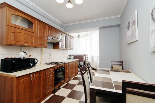 a kitchen with wooden cabinets and a table and a microwave at ERA RENT Apartments in Chişinău