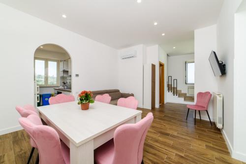 a living room with a white table and pink chairs at Relais Francesca Pool&View in Sorrento