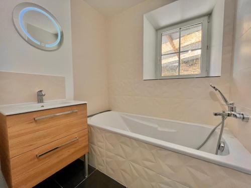 une salle de bain avec une baignoire, un lavabo et un miroir dans l'établissement T2 Rez-de-chaussée, Le Victor Hugo, à Cancale