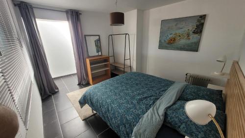 une chambre avec un lit avec une couverture bleue et une fenêtre dans l'établissement La Viste, chez Maya, à Marseille