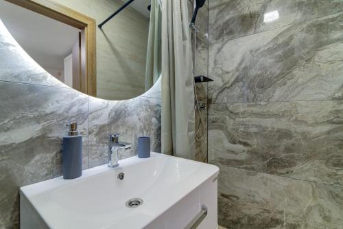 a bathroom with a white sink and a mirror at Apartmani Maka in Senj