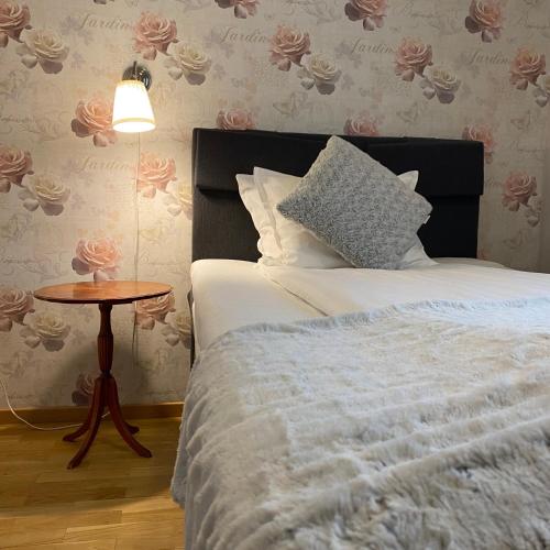 a bedroom with a bed and a table with a lamp at Smålandsstenar hotell in Smålandsstenar