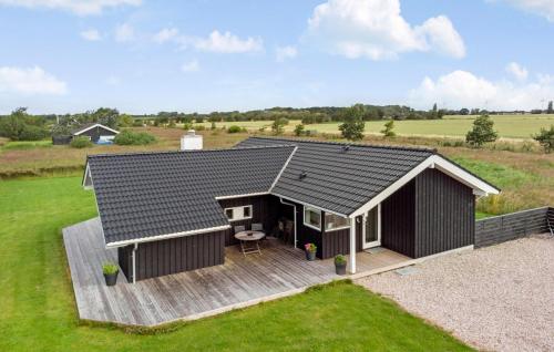 a black house with a wooden deck in a field at Stunning Home In Rødby With Wifi in Rødby