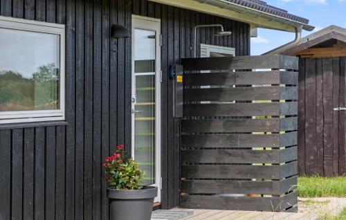 a wooden fence next to a black house with a flower pot at Stunning Home In Rødby With Wifi in Rødby