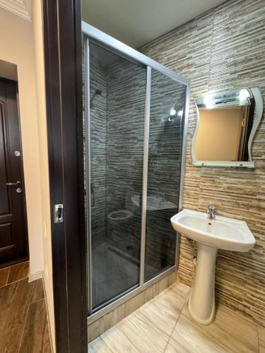 a bathroom with a glass shower and a sink at Pirosmani Mini Hotel in Batumi