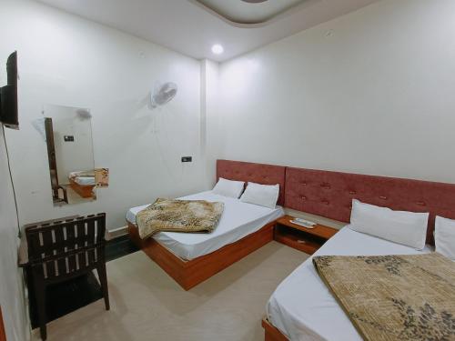 a hotel room with two beds and a chair at Hotel Shreem in Ujjain