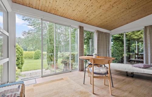 a living room with large windows and a table at Nice Home In Faxe Ladeplads With Wifi in Fakse Ladeplads